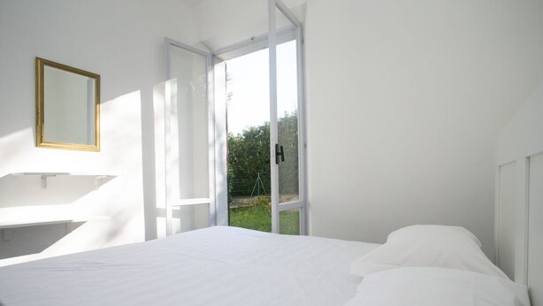Une chambre à coucher avec un lit, une fenêtre et un miroir au mur.