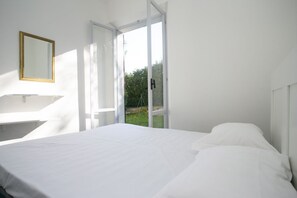 Un dormitorio con cama, ventana y espejo en la pared.
