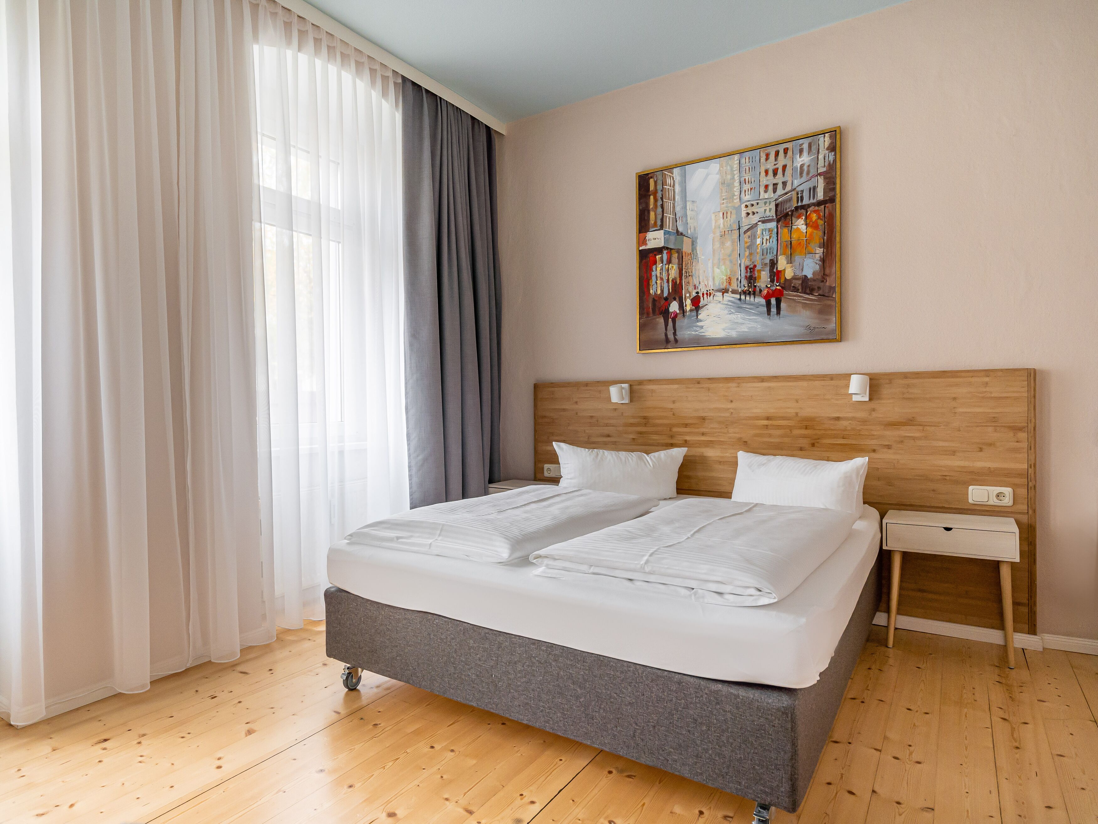 A hotel room with a large bed, a wooden headboard, a nightstand, and a painting on the wall.