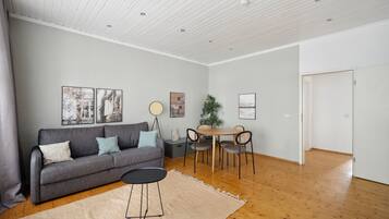 Un salon moderne avec un canapé gris, une table ronde et un coin repas.