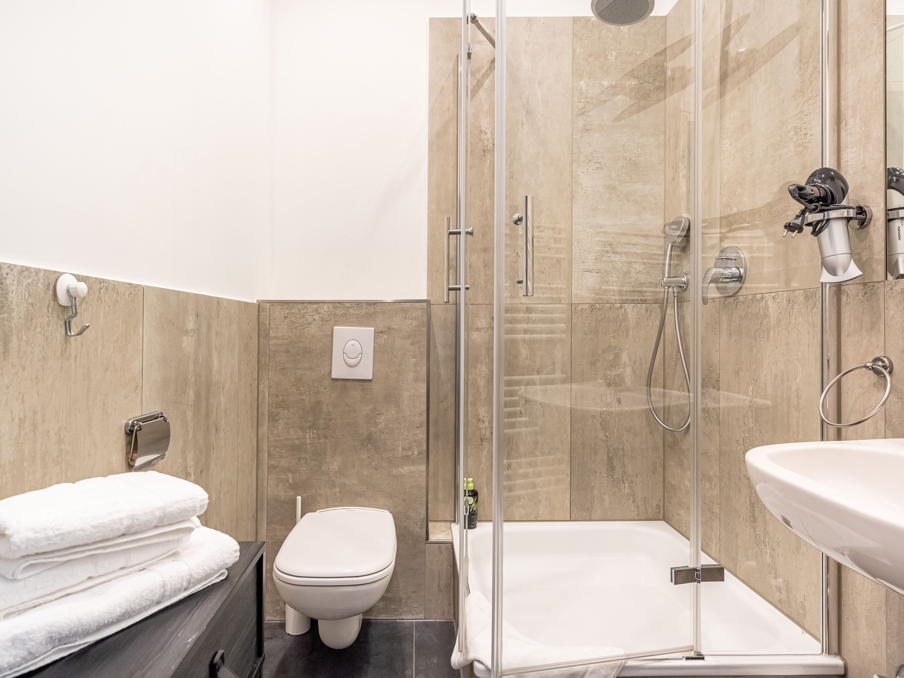 Un baño moderno con ducha acristalada, inodoro y lavamanos.