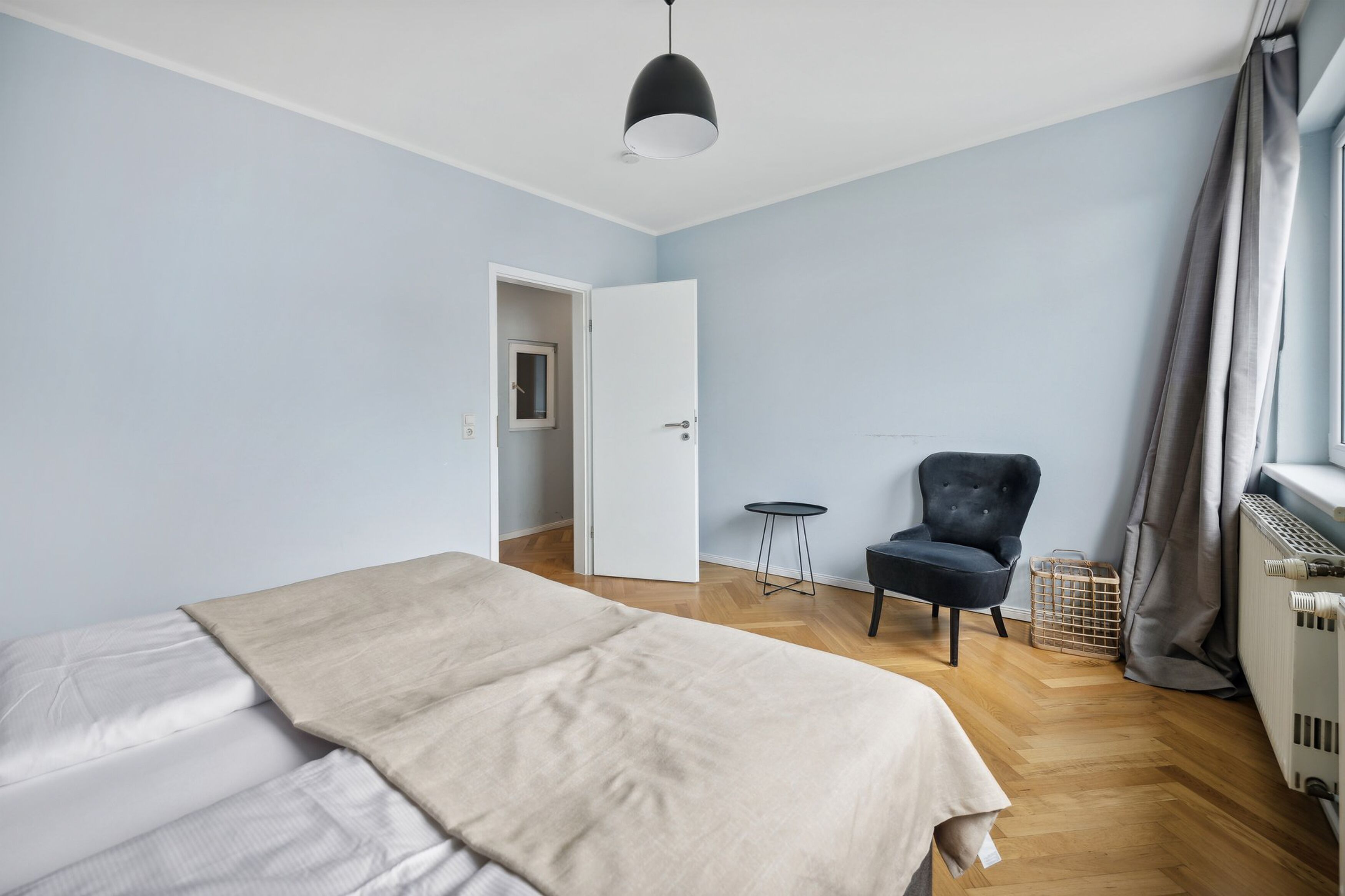 Une chambre à coucher avec un lit, une chaise, une petite table et un radiateur.