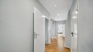 Un pasillo con puertas blancas y suelo de madera.