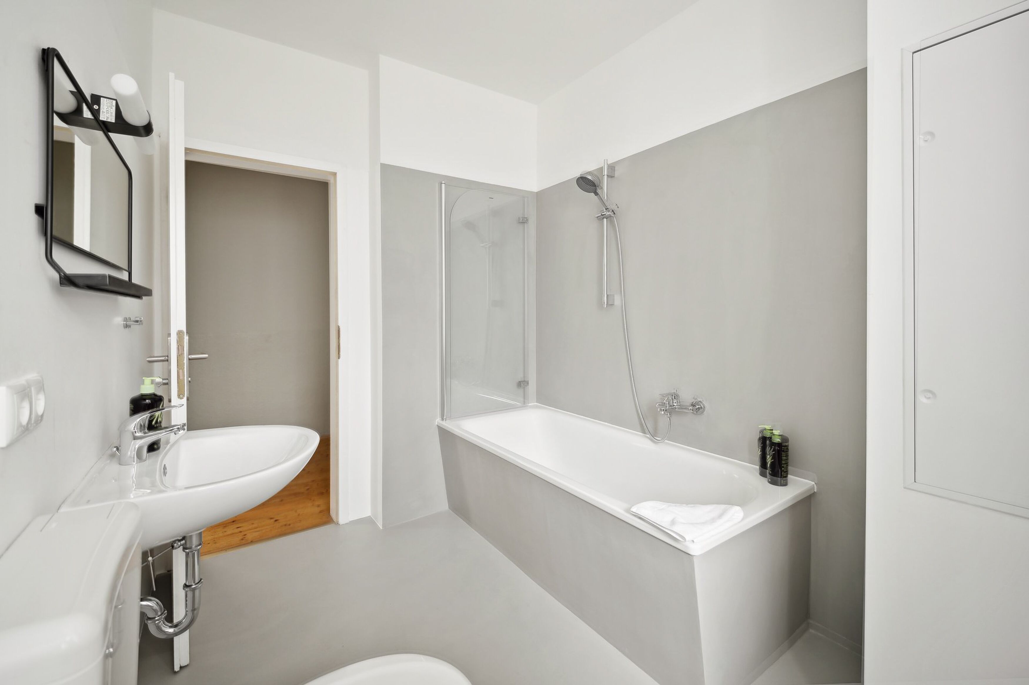 A modern bathroom with a white sink, a glass shower enclosure, and a white bathtub.