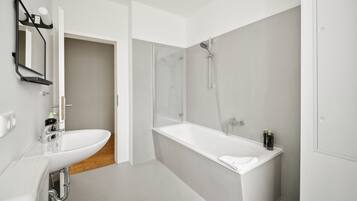 A modern bathroom with a white sink, a glass shower enclosure, and a white bathtub.
