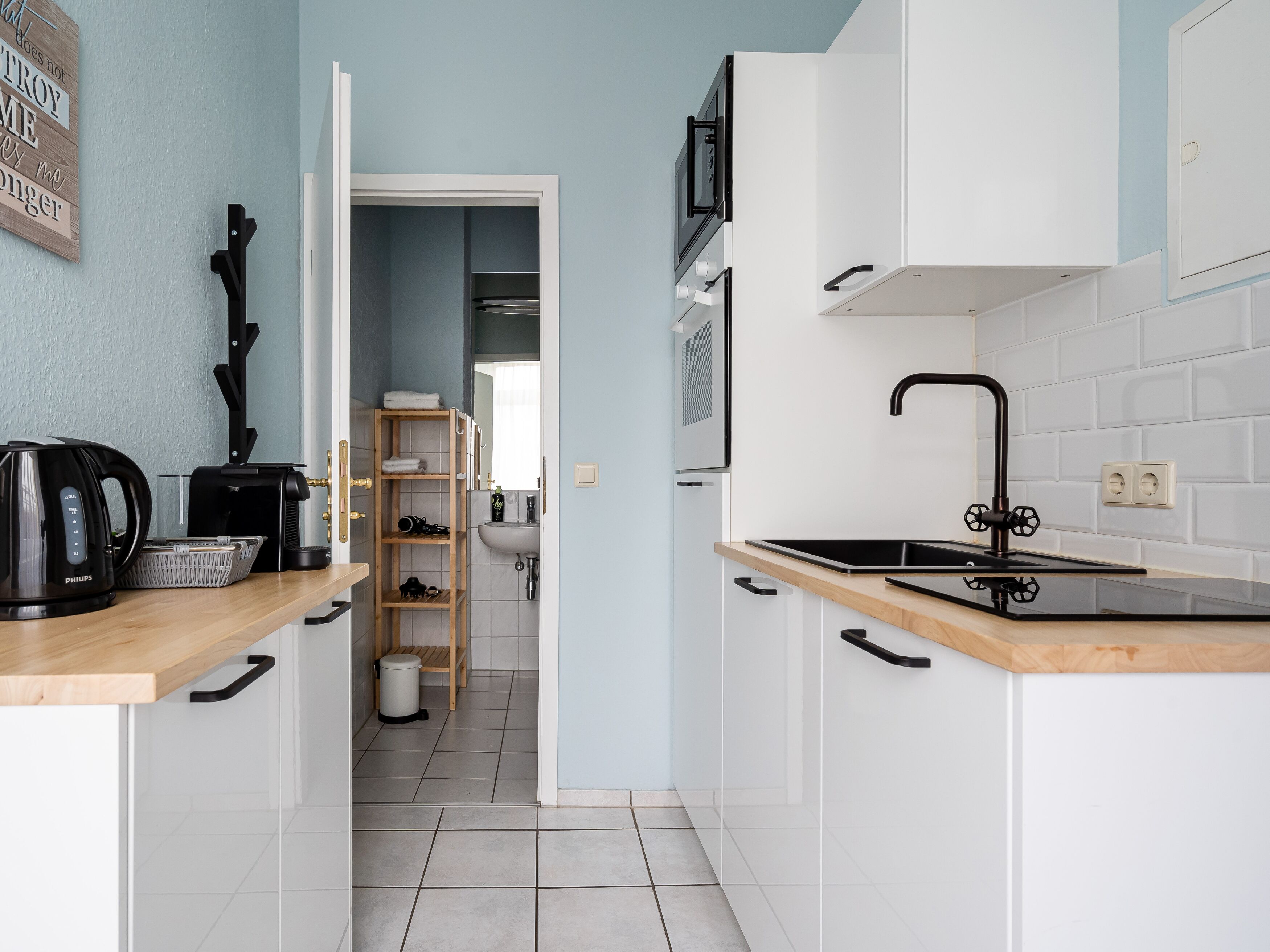 A modern kitchen with white cabinets, a black faucet, and a wooden countertop.