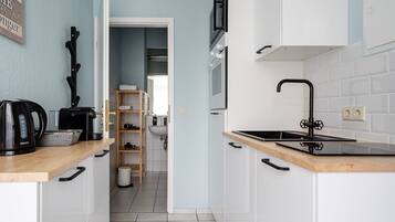 A modern kitchen with white cabinets, a black faucet, and a wooden countertop.