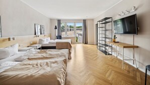 Una habitación de hotel moderna con dos camas, televisión, escritorio y vistas al balcón.