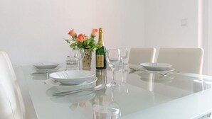 A dining table set with plates, cutlery, a bottle of champagne, and a vase of flowers. - Apartmani Marinović - Vodice (Vodice)