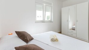 A bedroom with a bed, two pillows, a window, and a wardrobe. - Apartmani Marinović - Vodice (Vodice)