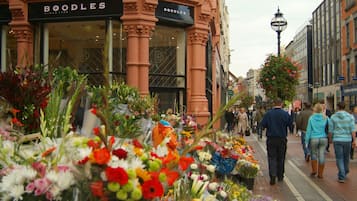 Una calle con una floristería y un edificio con un letrero que dice "BOODLES".