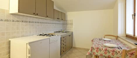 A compact kitchen with a gas stove, a dishwasher, and a dining table with chairs.