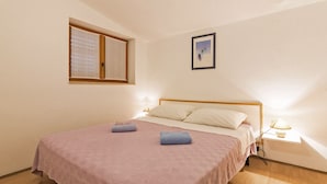 Ein Schlafzimmer mit Bett, Fenster, Nachttisch und einem Wandbild.