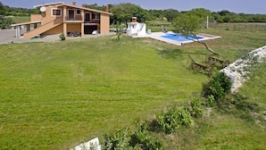 Ein zweigeschossiges Haus mit Swimmingpool, umgeben von einem Rasen und Bäumen.