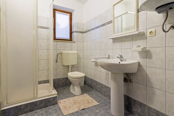 Un baño con ducha, inodoro, lavabo y ventana.