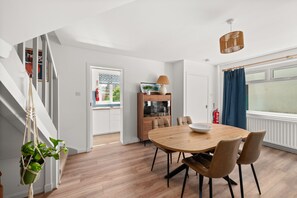 Ein stilvoller Essbereich mit Holztisch und -stühlen, einer hängenden Pflanze und Blick ins Freie.
