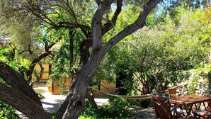 An outdoor patio with a wooden table and chairs, surrounded by trees and greenery. - Casa Champasak, Alpujarra Granada, VTAR/GR/01097 (Las Barreras - Órgiva)