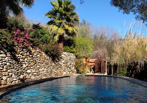 A swimming pool with a stone wall and a wooden structure in the background. - Casa Champasak, Alpujarra Granada, VTAR/GR/01097 (Las Barreras - Órgiva)