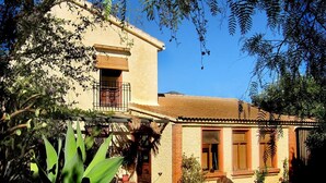 A two-story building with a balcony, potted plants, and a garden area. - Casa Champasak, Alpujarra Granada, VTAR/GR/01097 (Las Barreras - Órgiva)