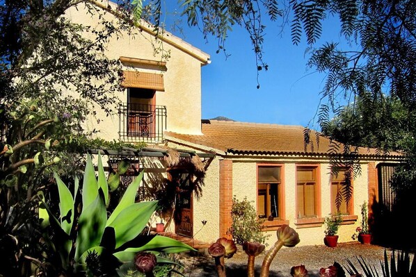 A two-story building with a balcony, potted plants, and a garden area. - Casa Champasak, Alpujarra Granada, VTAR/GR/01097 (Las Barreras - Órgiva)