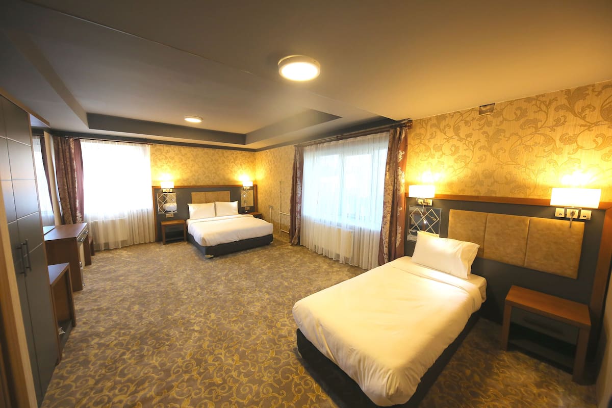 A hotel room with two beds, a wardrobe, a desk, and a nightstand.