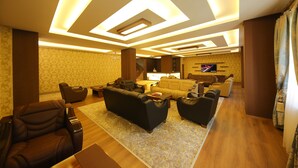 A modern living room with a sofa, armchairs, and a coffee table. There is a television mounted on the wall and a patterned rug on the floor. - Taht Palace Hotel (Van)