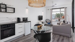 Una cucina moderna con piano cottura nero, pensili bianchi e un tavolo da pranzo in vetro.