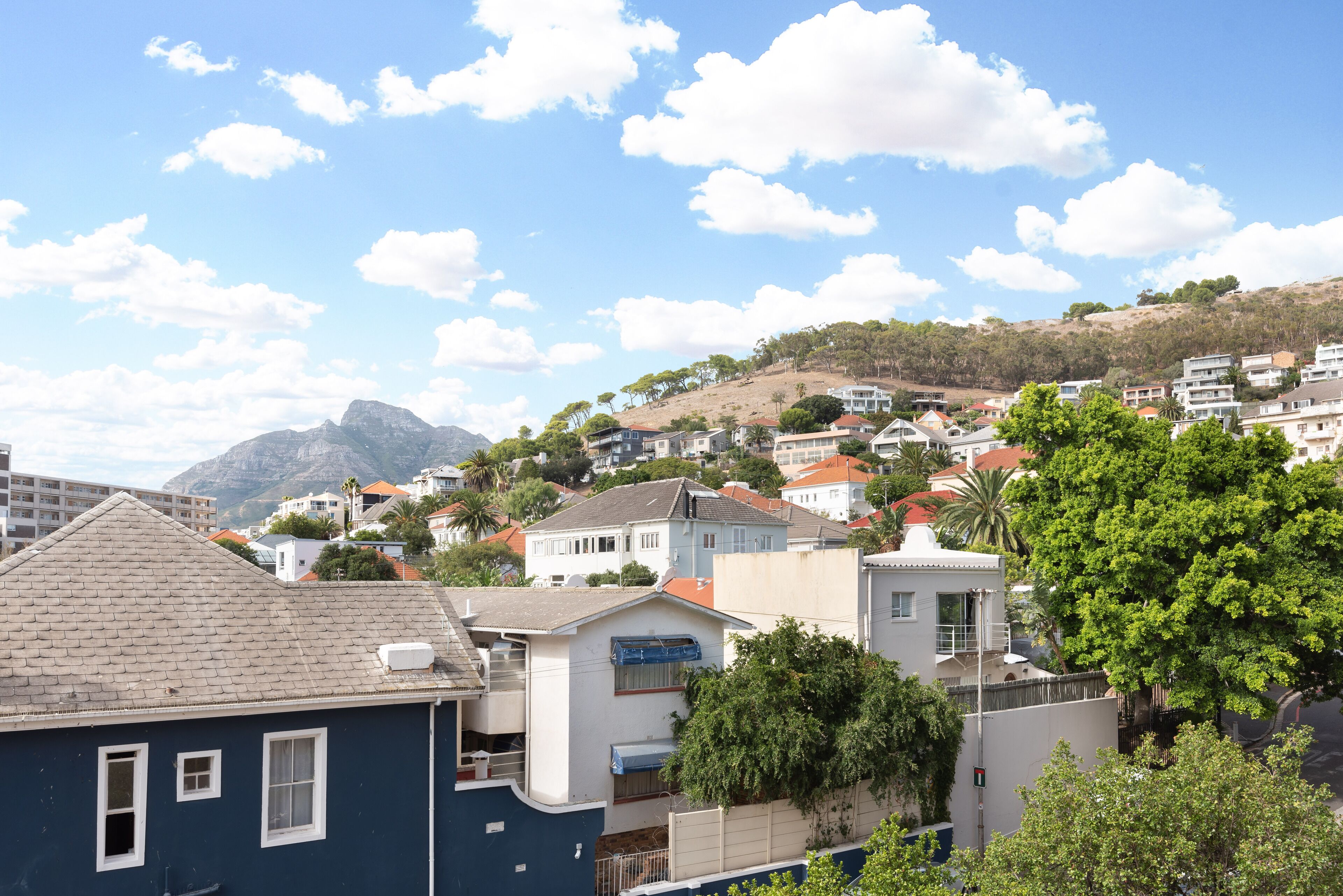 Et boligområde med huse, hvoraf nogle har røde tage, og et bjerg i baggrunden.