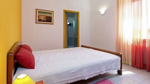 Een slaapkamer met een bed, een bedlamp, een deur en een raam met gordijnen.