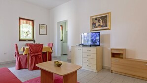 Een woonkamer met een eethoek, een televisie en een kast.