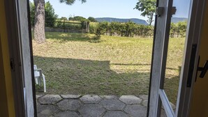 Vista da una porta su una zona erbosa all'aperto, con un sentiero lastricato in pietra che conduce a una sedia bianca.