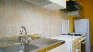Una cucina con lavello in acciaio inossidabile, piano cottura a gas, forno integrato e lavatrice.