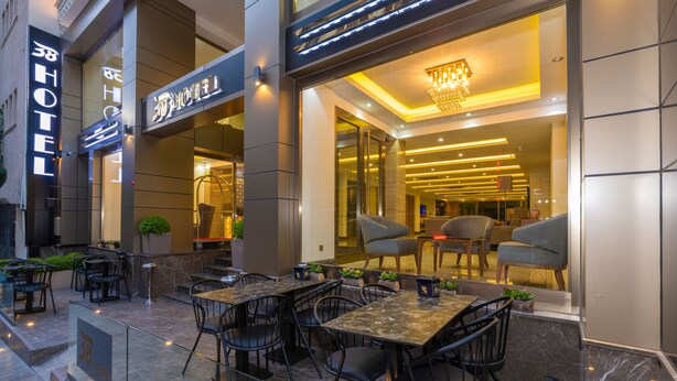 Un espace extérieur aménagé avec des tables et des chaises, une cloison en verre et une enseigne indiquant un hôtel.