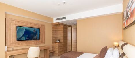 Habitación de hotel con dos camas, un escritorio, una silla, un televisor y un cuadro en la pared.