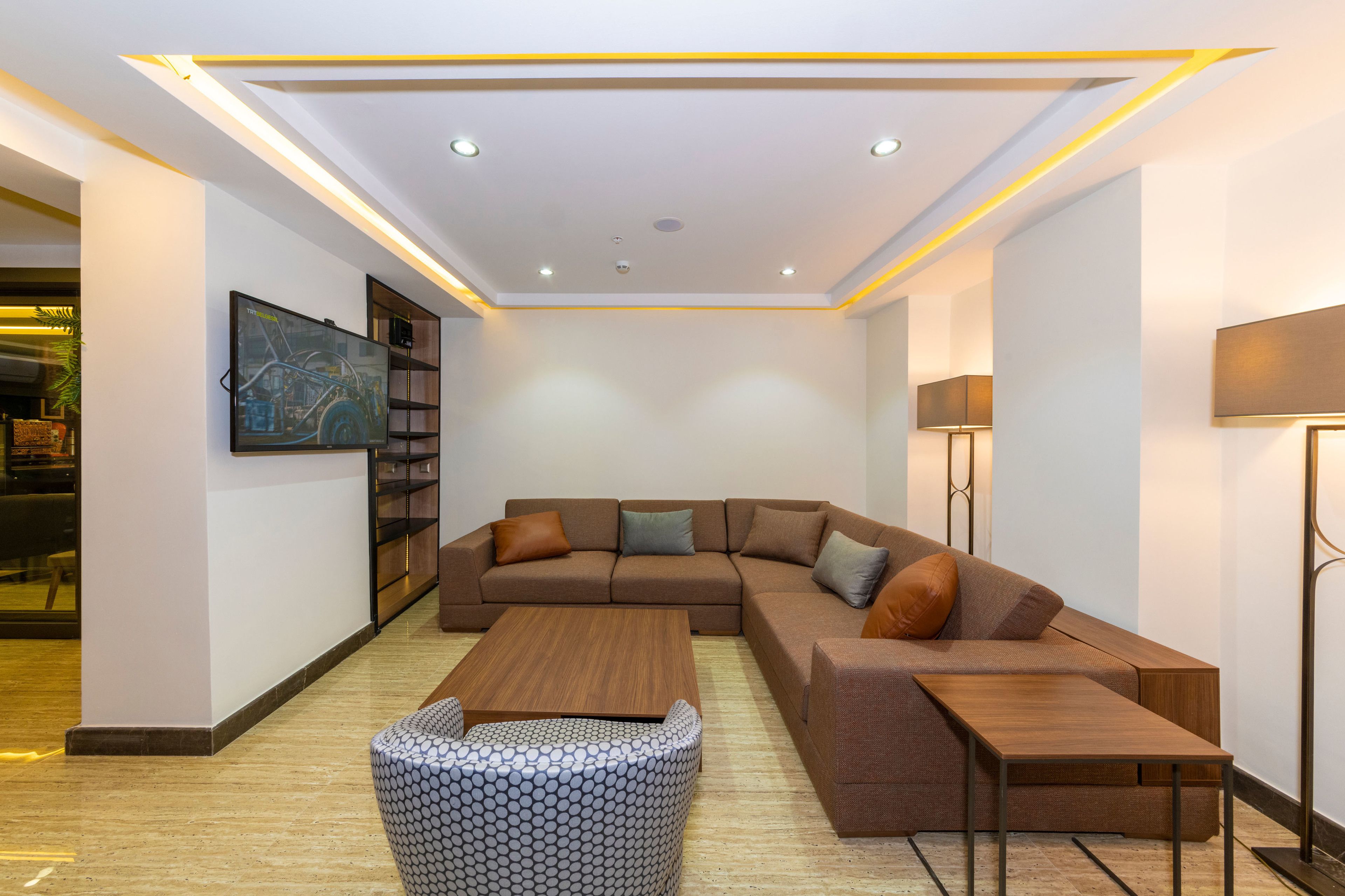 A modern living room with a sectional sofa, a coffee table, and a patterned ottoman.