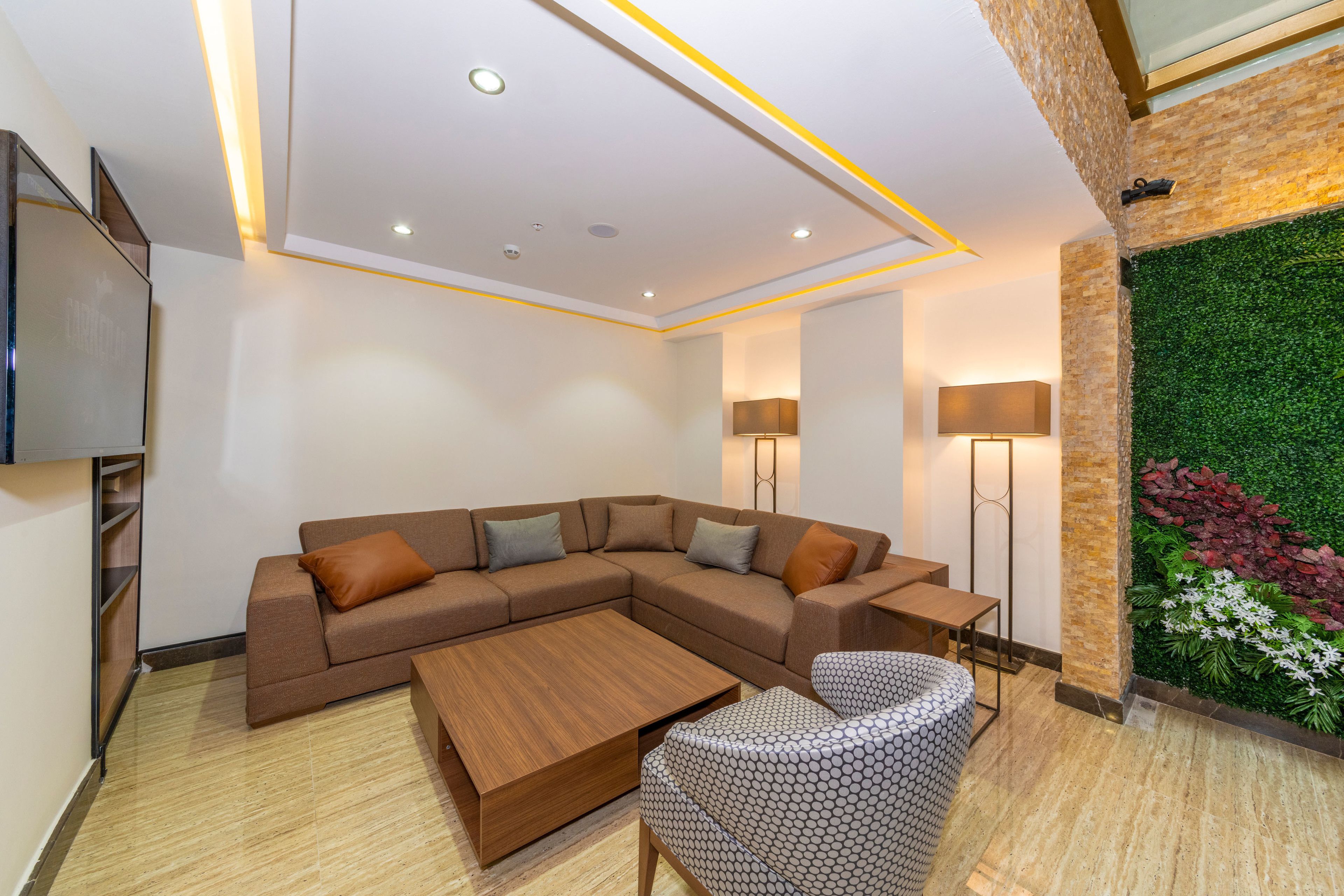 Una sala de estar moderna con un sofá modular, una mesa de centro, un sillón estampado y una pared decorada en tonos verdes.