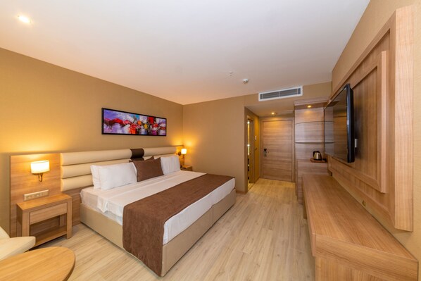 A modern hotel room with a large bed, bedside tables, a flat-screen TV, and a painting on the wall.