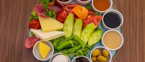 Una bandeja con quesos, embutidos, verduras y salsas.