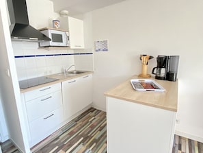 A compact kitchen with white cabinets, a microwave, a sink, and a coffee maker. - House 150m from beach, pool, WIFI, parking (Bretignolles-sur-Mer)