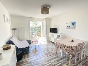 A modern living room with a sofa, a small table, a television, and a patterned floor. - House 150m from beach, pool, WIFI, parking (Bretignolles-sur-Mer)