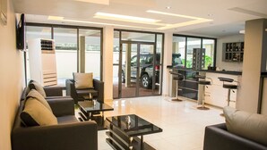 A modern hotel lobby with seating areas, a bar, and a view of parked cars outside. - Ziroc Residence (Lekki)