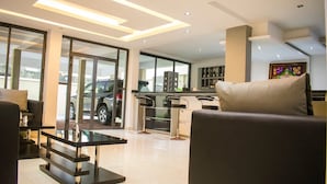 A modern living room with a glass coffee table, a sofa, and a bar area with stools. - Ziroc Residence (Lekki)