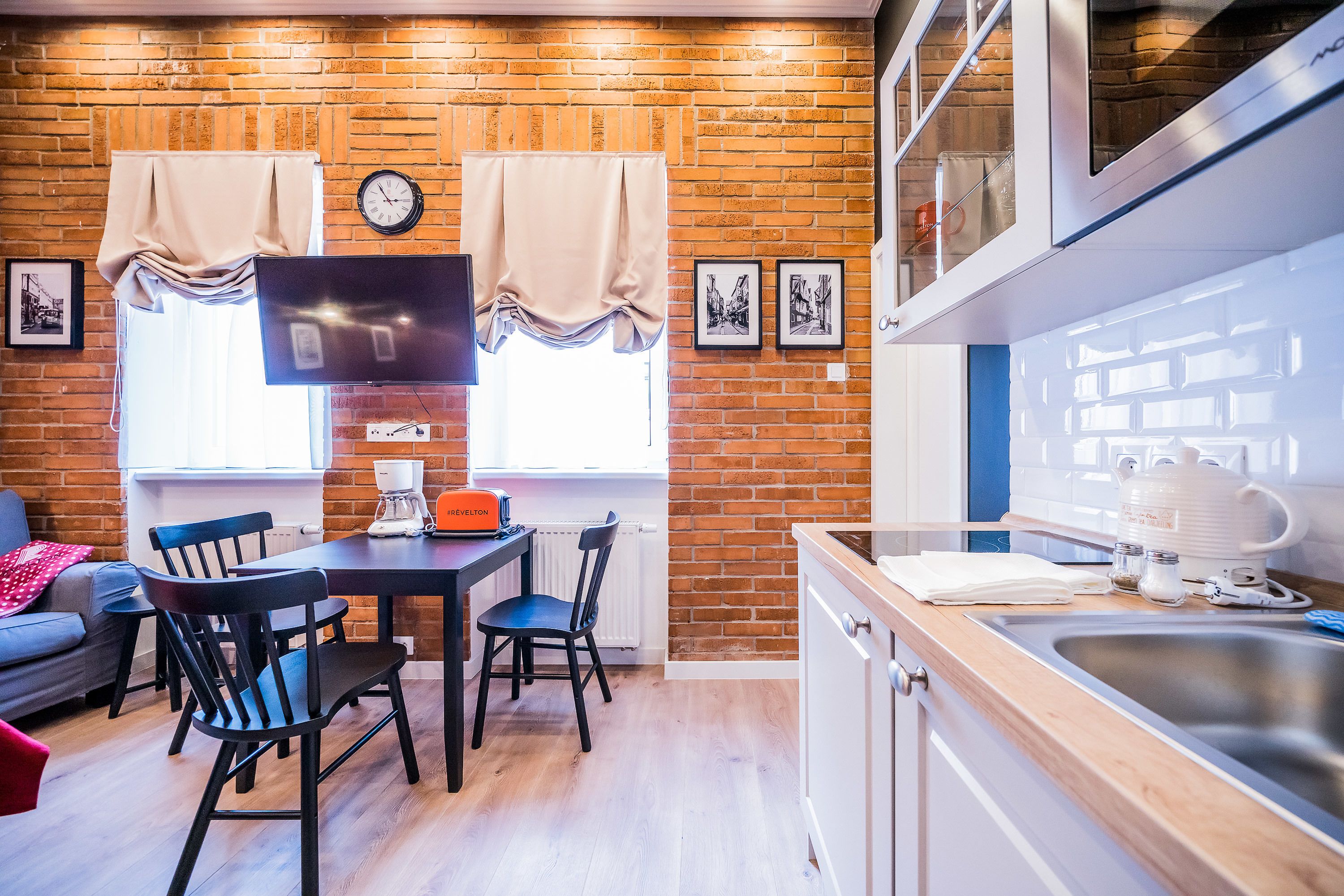 Un espace de vie compact comprenant un coin repas, une cuisine et un mur en briques.