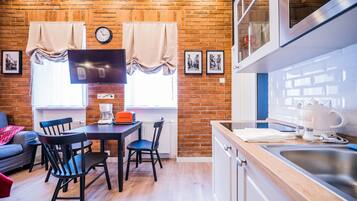 Un espace de vie compact comprenant un coin repas, une cuisine et un mur en briques.
