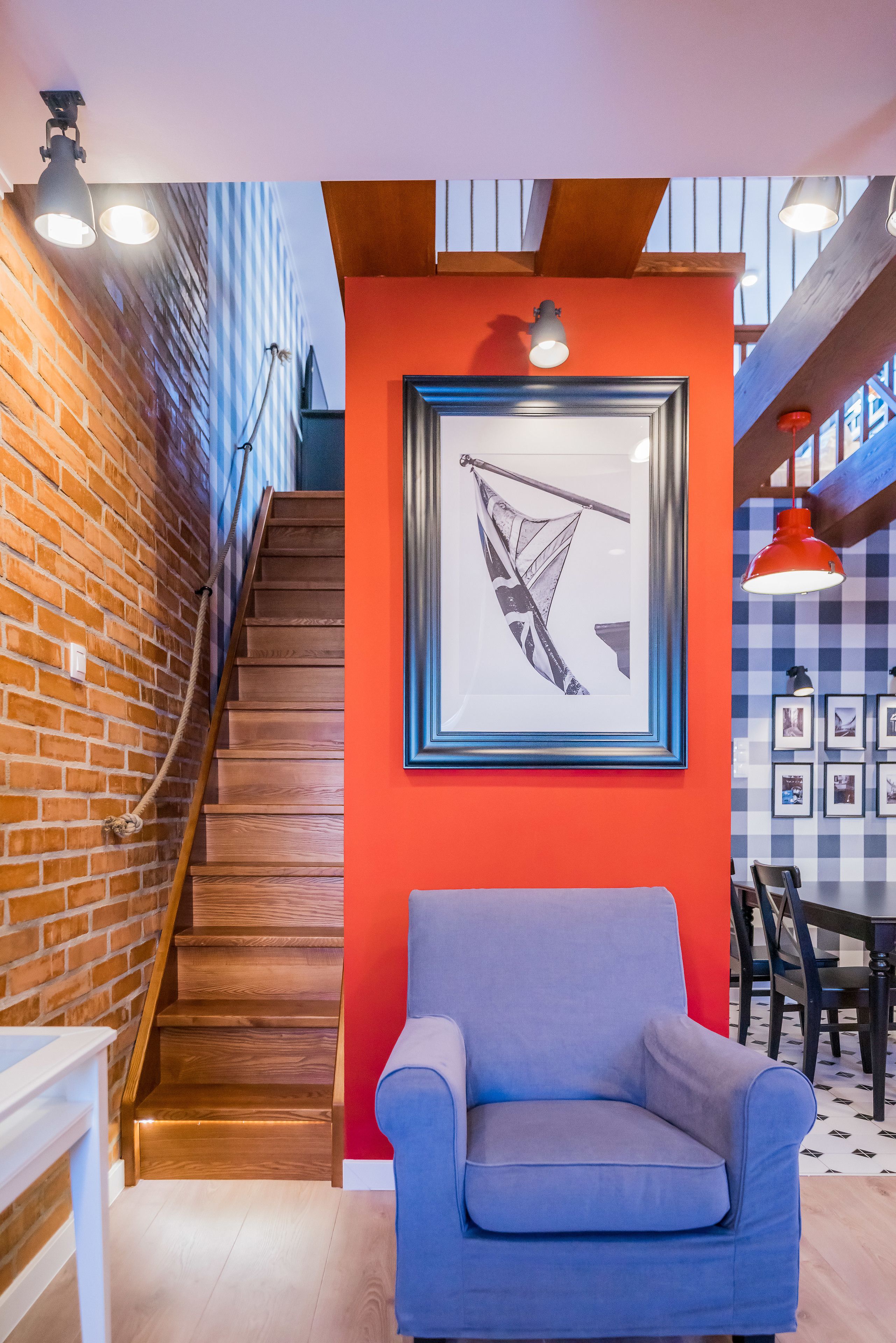 A staircase with wooden steps and a red wall with a framed picture.