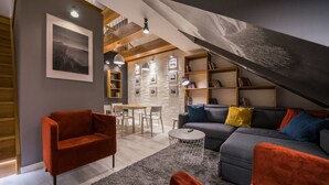 A modern living room with a sofa, armchairs, and a dining area.