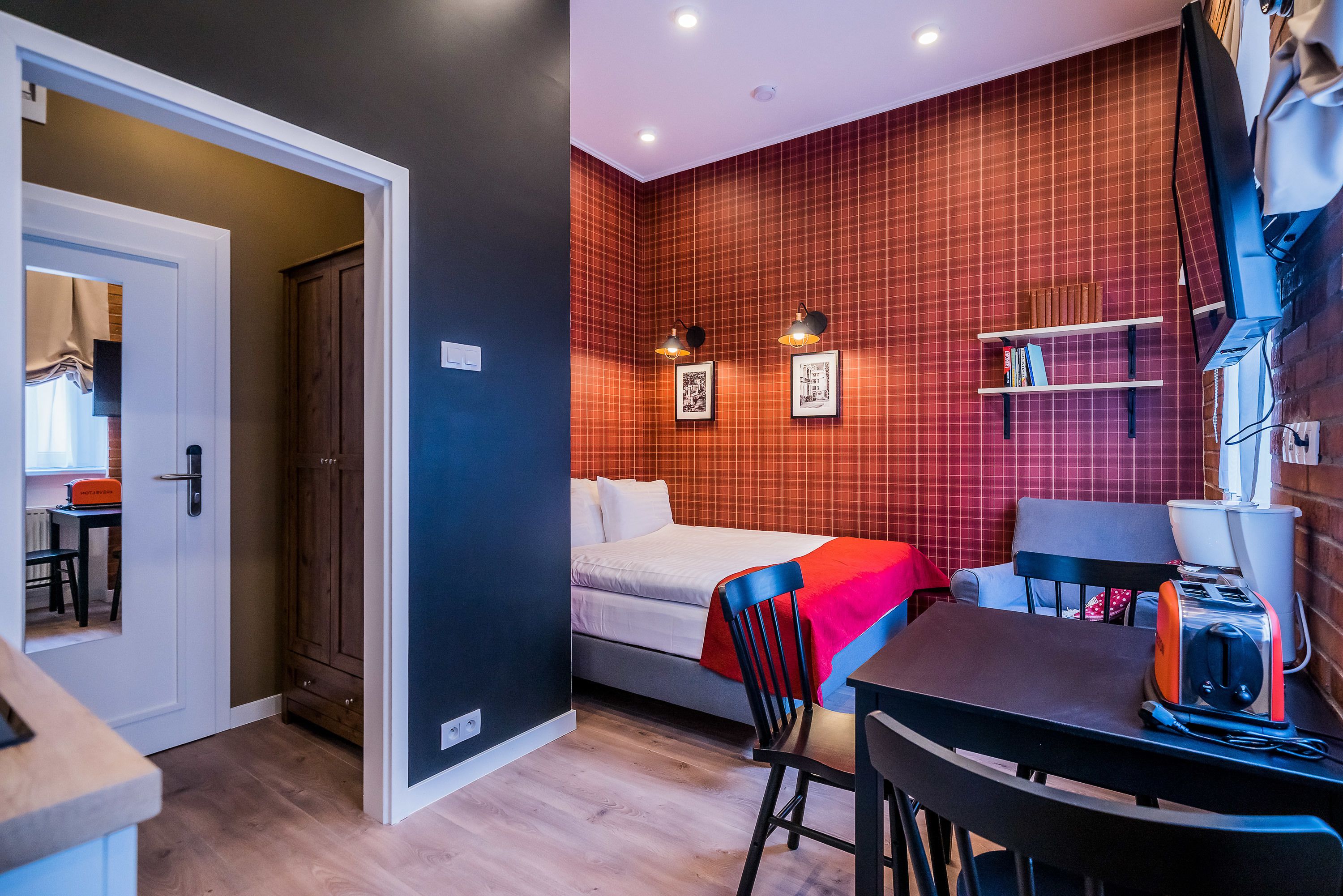 A compact room with a bed, a desk, a chair, and a shelf with books.