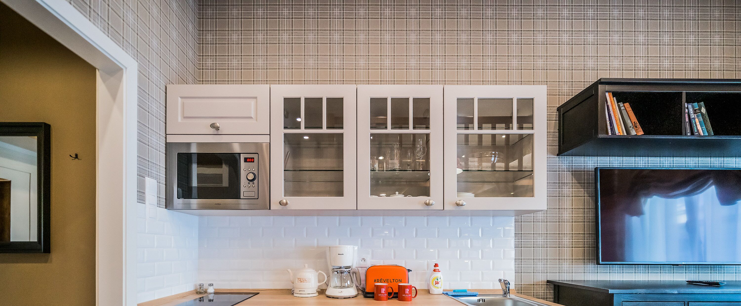 Una cocina con armarios blancos, microondas, cafetera y tostadora.