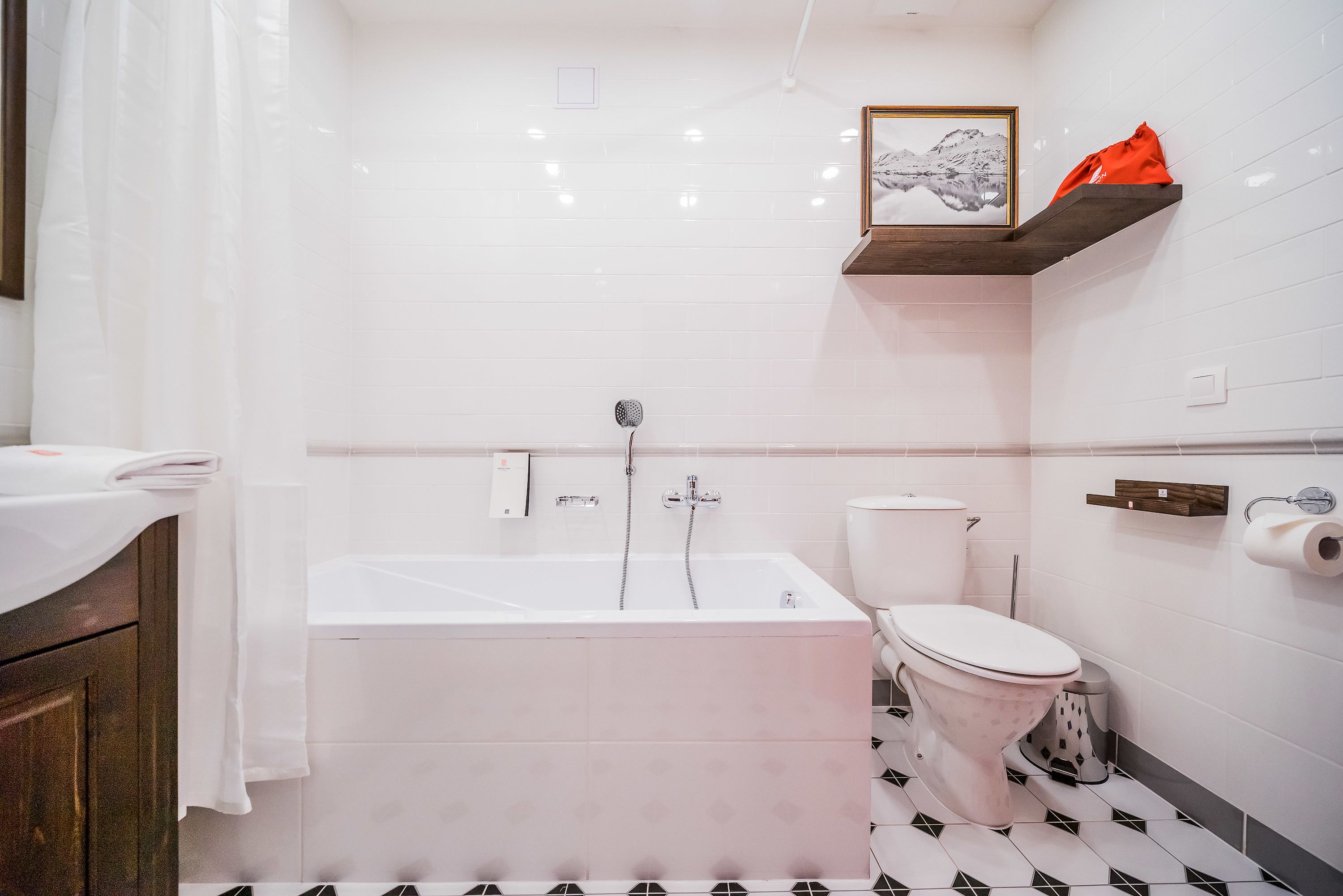 Un bagno con vasca, WC e ripiano con una cornice e un'immagine.