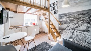 A modern interior with a loft bedroom, a kitchen, and a dining area.